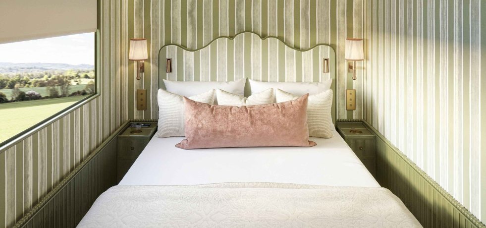 “Belmond Britannic luxury train cabin bedroom with king bed and panoramic window view of the British countryside at sunrise