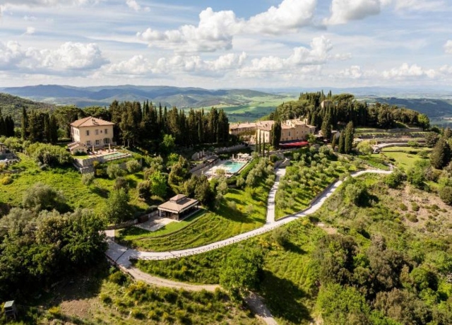Aerial view of the infinity pool at Rosewood Castiglion del Bosco with panoramic views of Tuscan vineyards and rolling hills